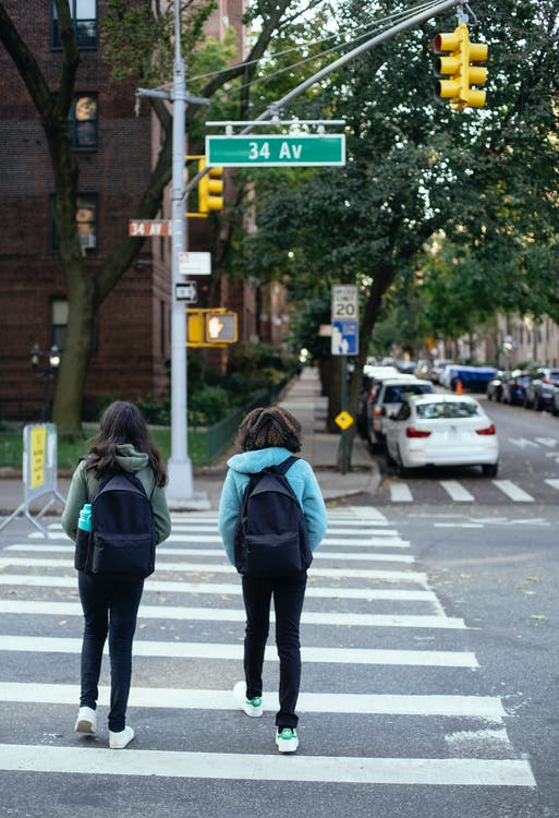 Two Students Crossing the Road at a Pedestrian Crossing